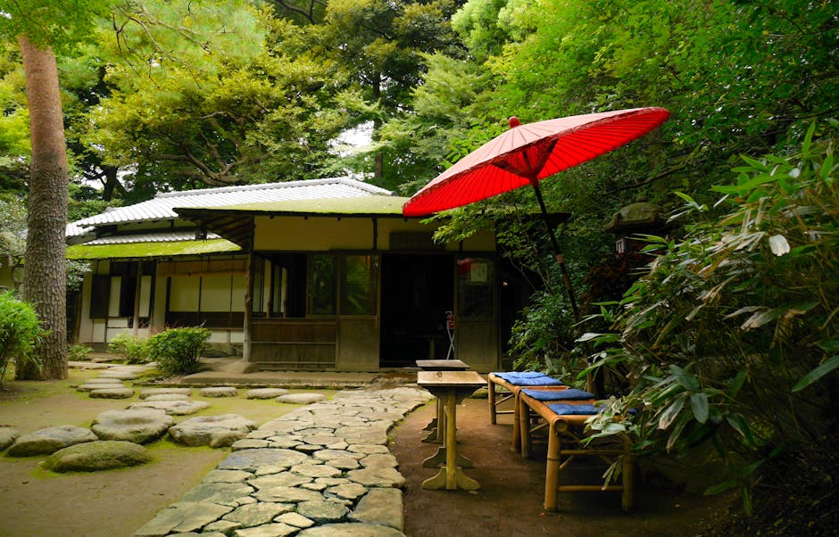 Serene Japanese garden featuring bamboo furniture and red sunshade, ideal for tranquil moments.